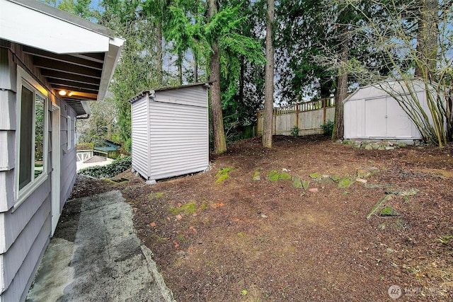 view of yard featuring an outbuilding, a storage shed, and fence