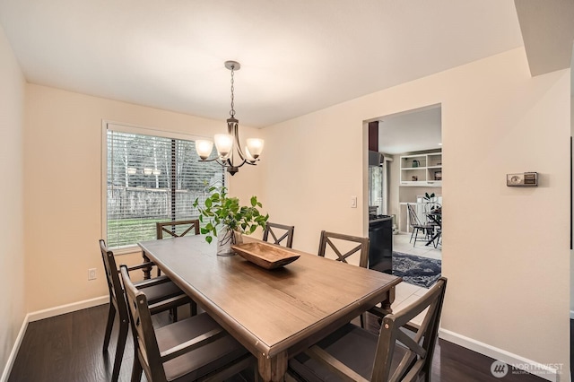 dining room featuring a chandelier, baseboards, and dark wood-style flooring