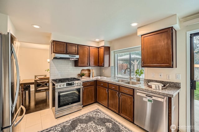 kitchen with tasteful backsplash, under cabinet range hood, light tile patterned floors, stainless steel appliances, and a sink