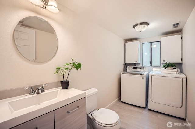 bathroom featuring visible vents, toilet, washer and clothes dryer, baseboards, and vanity