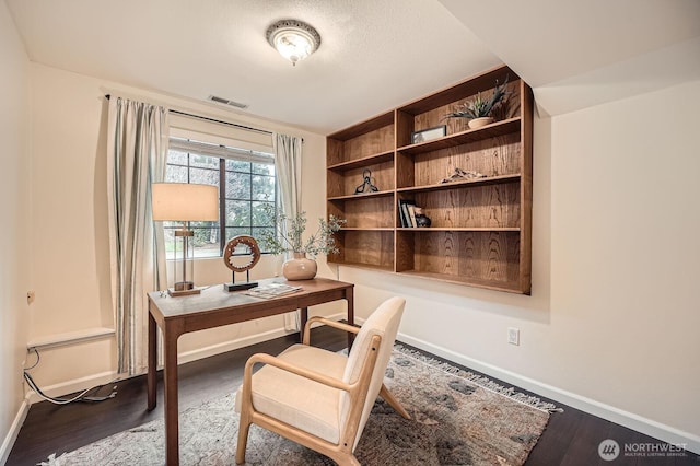 office area with wood finished floors, visible vents, and baseboards