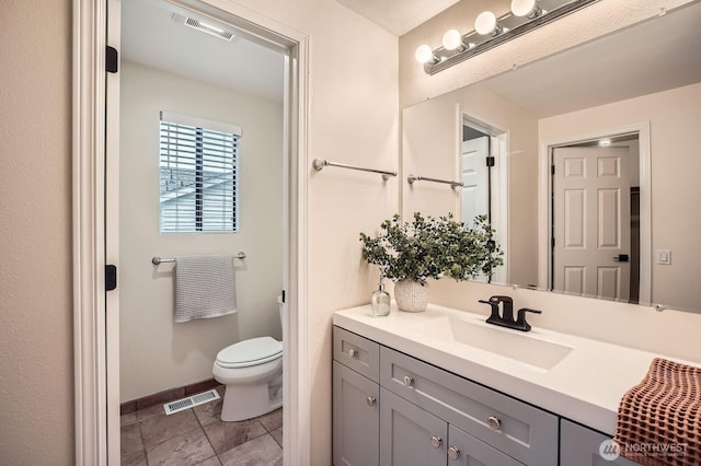 bathroom with visible vents, toilet, vanity, and baseboards