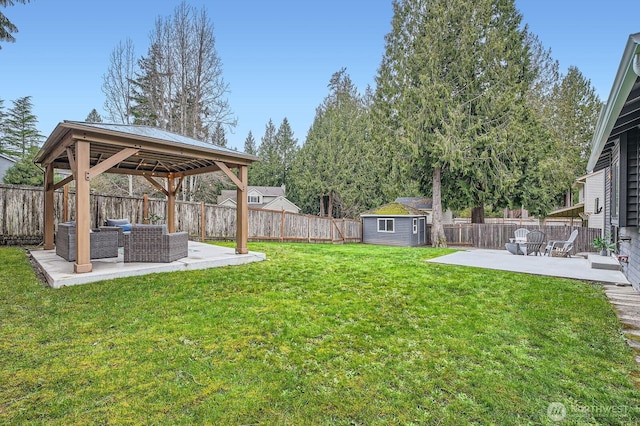 view of yard featuring a patio, an outbuilding, a shed, a fenced backyard, and a gazebo