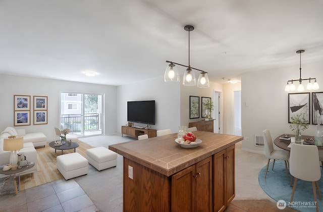 kitchen with light tile patterned floors, open floor plan, brown cabinets, and a kitchen island