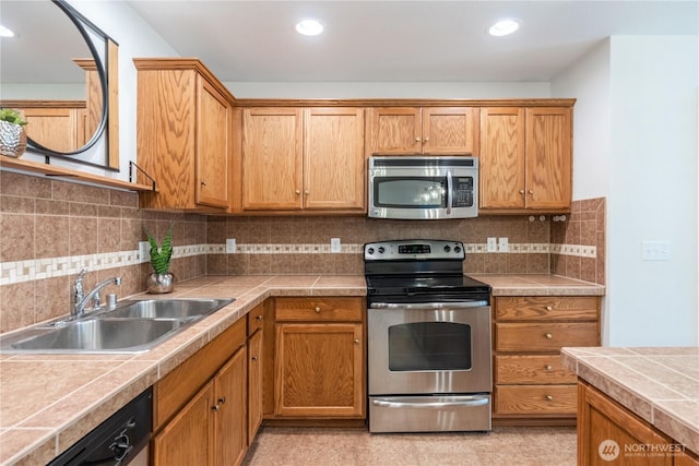 kitchen featuring a sink, tile countertops, recessed lighting, appliances with stainless steel finishes, and decorative backsplash