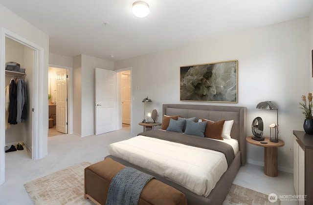 bedroom with a closet, light colored carpet, a walk in closet, and baseboards