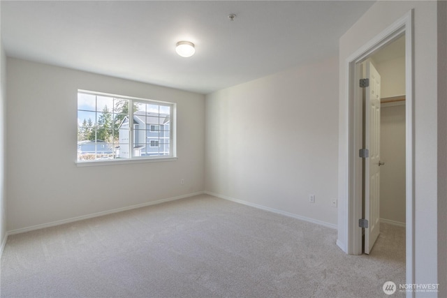 unfurnished bedroom featuring a closet, carpet flooring, a walk in closet, and baseboards