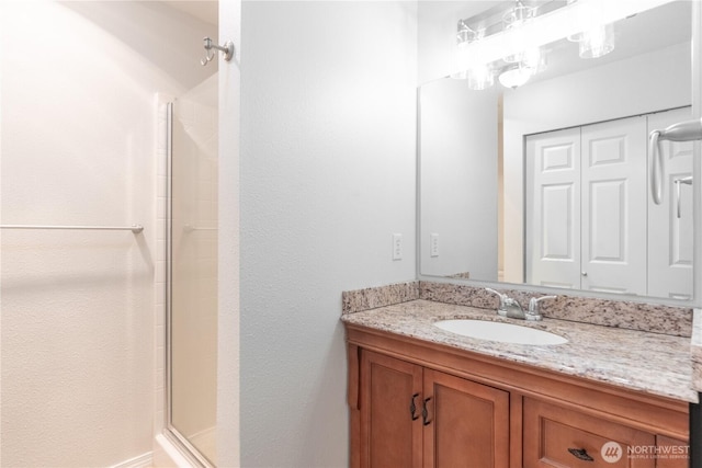 full bath featuring a shower with door and vanity