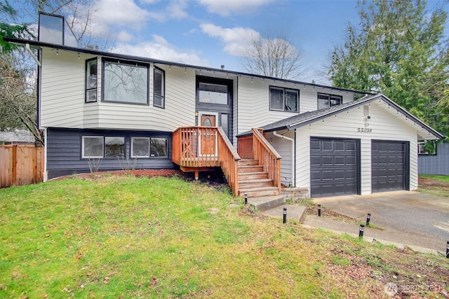 bi-level home with driveway, a front lawn, a garage, and fence