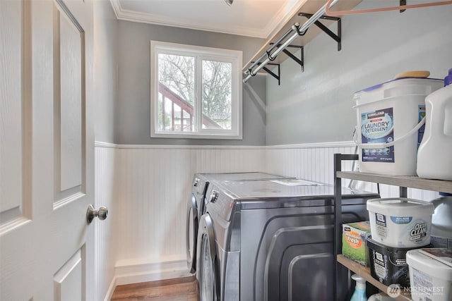 clothes washing area featuring laundry area, independent washer and dryer, ornamental molding, and a wainscoted wall