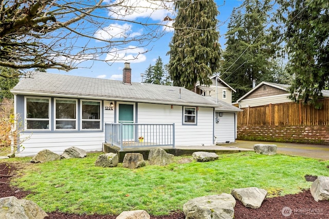 rear view of house with a lawn, a chimney, and fence