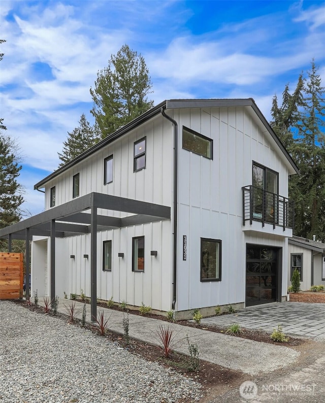 view of home's exterior with a balcony, an attached garage, board and batten siding, and driveway