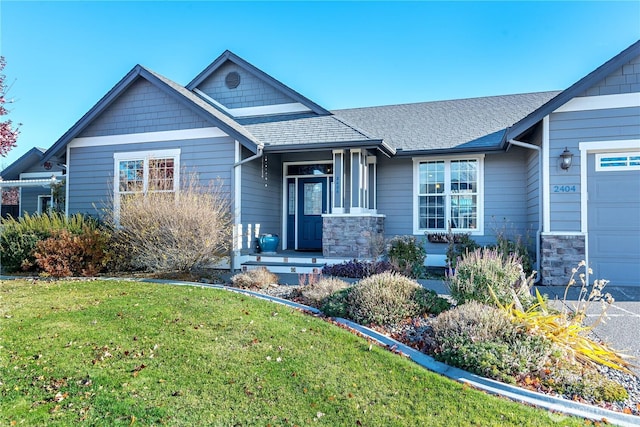 view of front facade with a front yard, a garage, stone siding, and roof with shingles