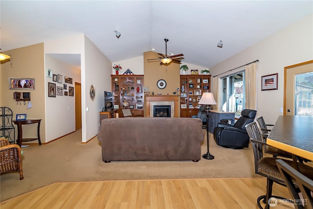 living room featuring ceiling fan, a tile fireplace, light wood-type flooring, and lofted ceiling