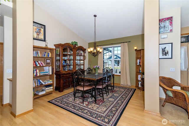 dining room with a notable chandelier, light wood-style floors, and vaulted ceiling