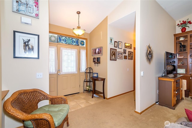 entrance foyer featuring baseboards, lofted ceiling, and light colored carpet