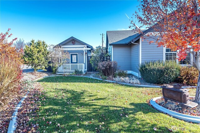 view of front of house with a front lawn, covered porch, and a shingled roof