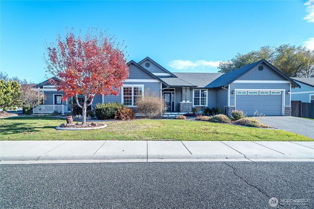 view of front of house with driveway, a front lawn, stone siding, fence, and a garage