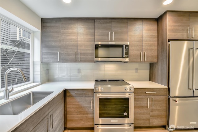 kitchen featuring recessed lighting, a sink, decorative backsplash, light countertops, and appliances with stainless steel finishes