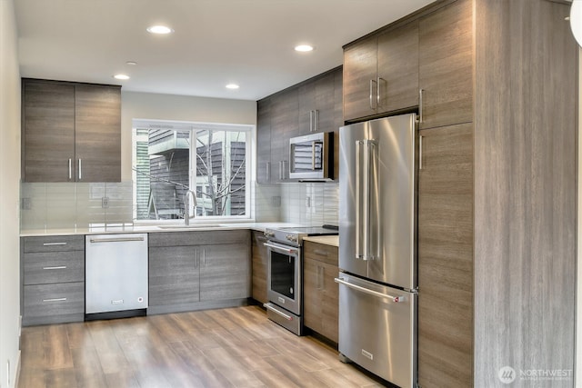 kitchen featuring modern cabinets, tasteful backsplash, appliances with stainless steel finishes, and a sink