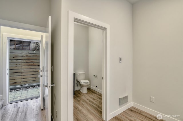 bathroom featuring toilet, wood finished floors, visible vents, and baseboards