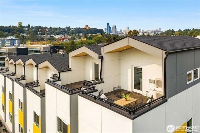 exterior space featuring a view of city, roof with shingles, and stucco siding