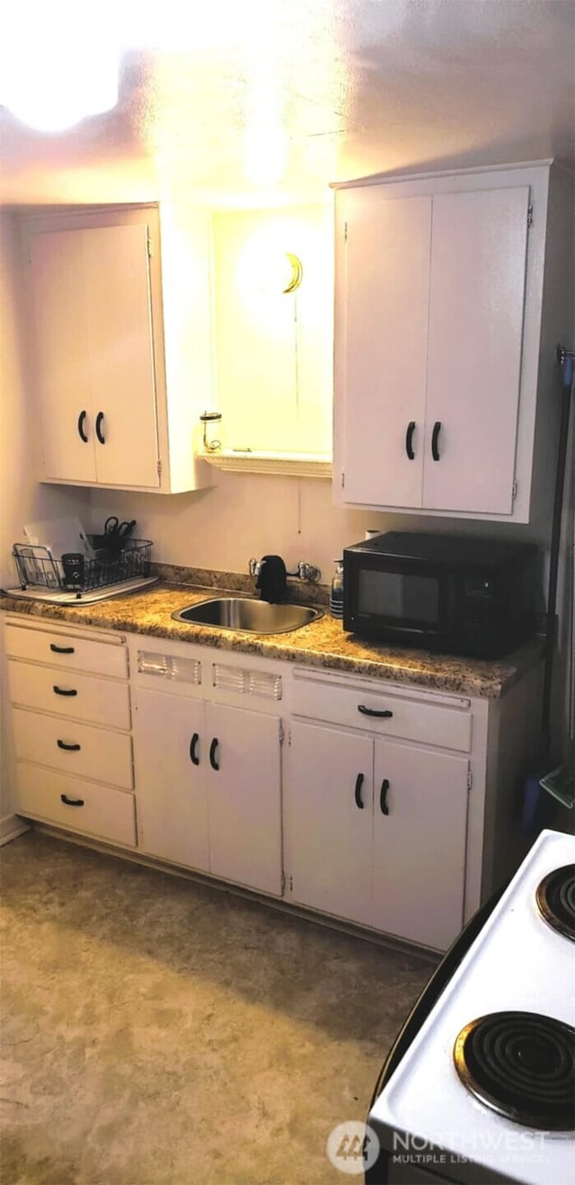 kitchen with electric range, white cabinetry, black microwave, and a sink