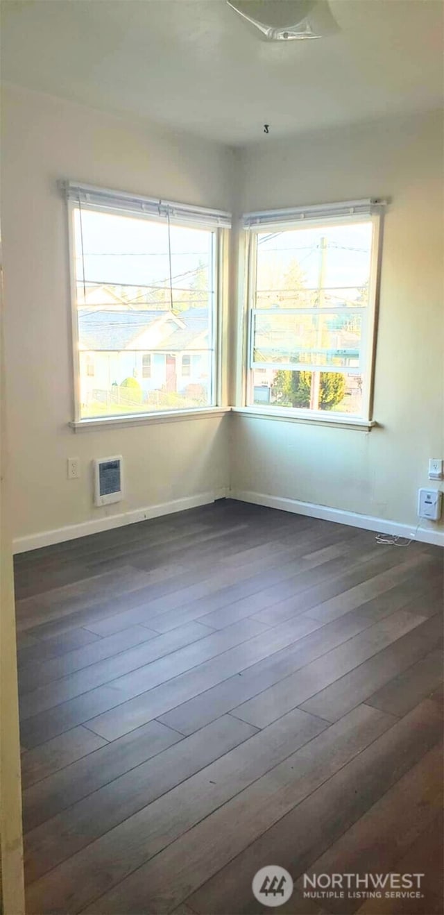 empty room featuring baseboards and dark wood-style flooring