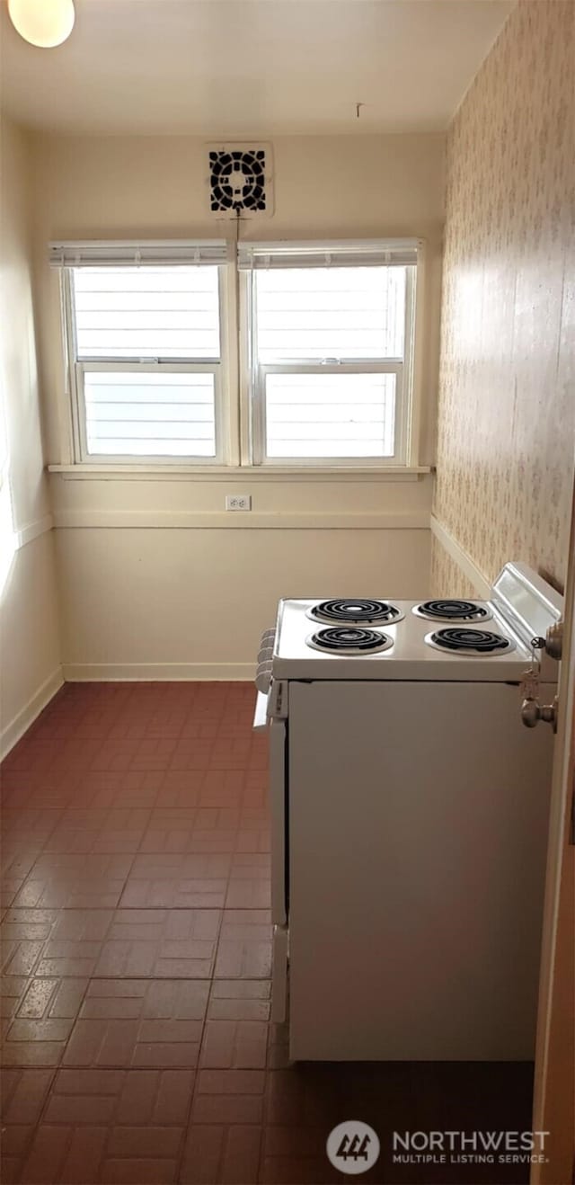 kitchen with white electric stove, baseboards, and a wealth of natural light