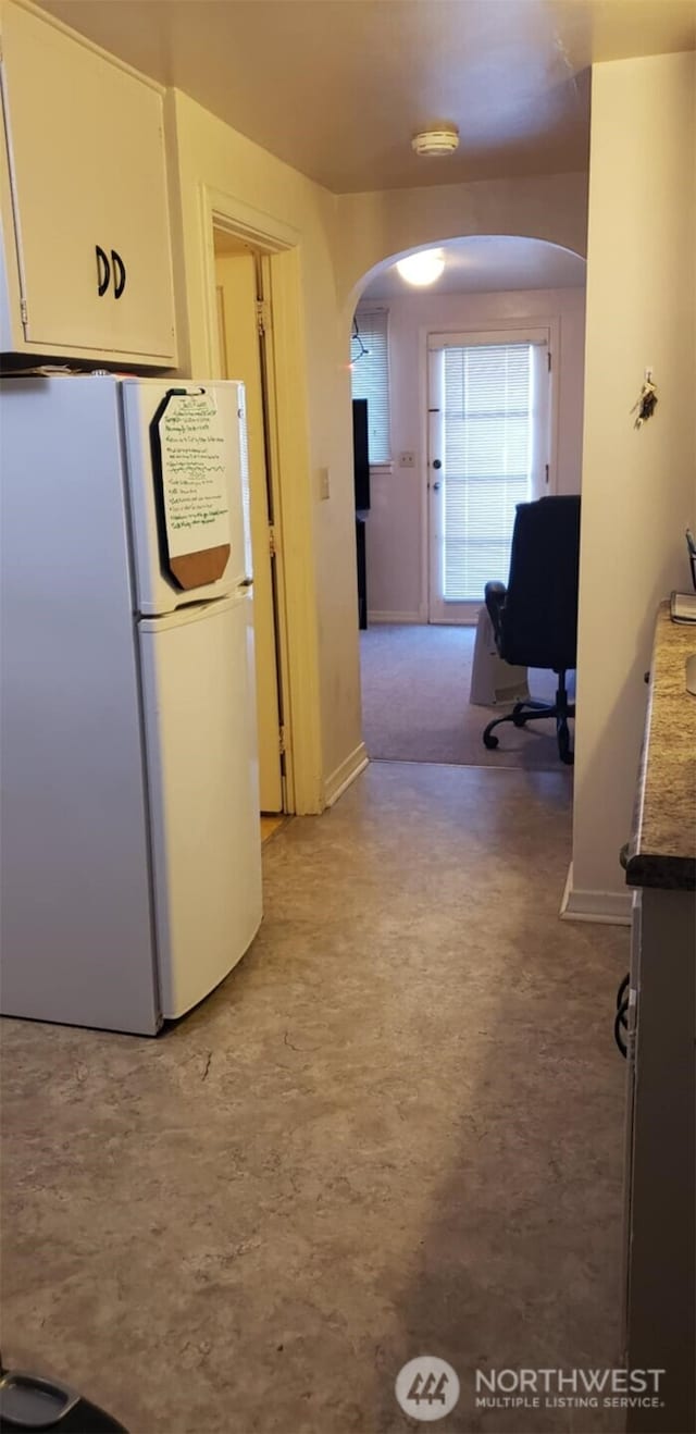 hallway featuring baseboards and arched walkways