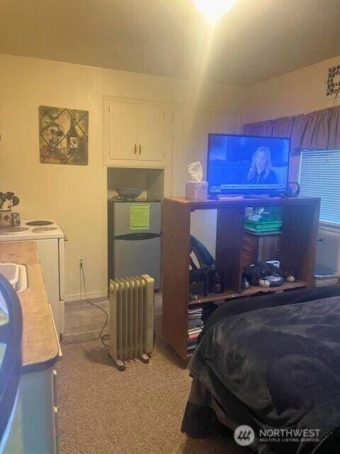 bedroom with freestanding refrigerator, carpet flooring, radiator heating unit, and separate washer and dryer