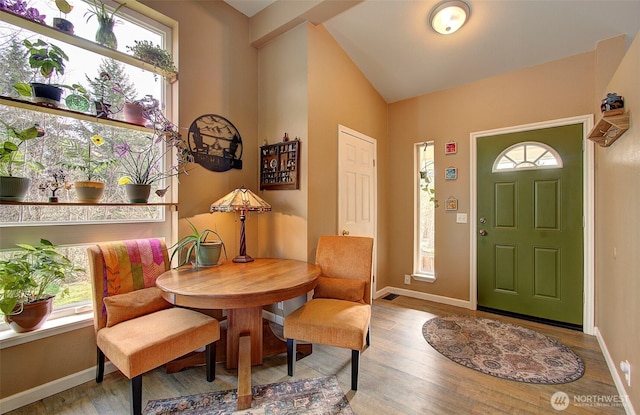 foyer featuring baseboards, wood finished floors, and vaulted ceiling