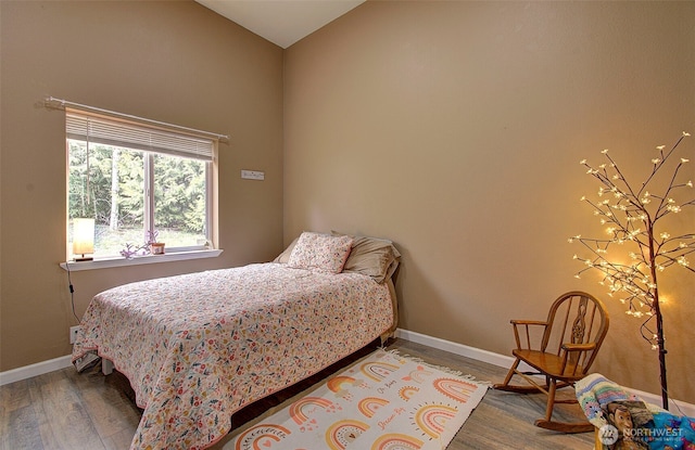 bedroom with baseboards, lofted ceiling, and wood finished floors