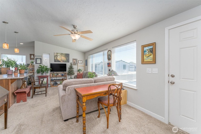 living room with baseboards, ceiling fan, vaulted ceiling, light carpet, and a textured ceiling