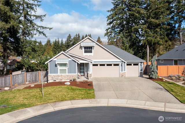 view of front of house featuring driveway, stone siding, fence, a front yard, and a garage