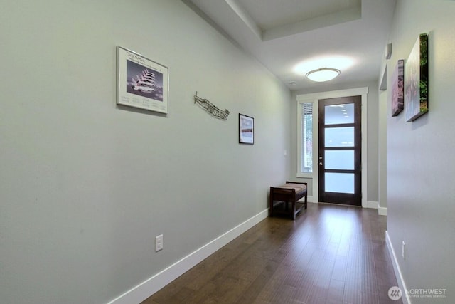 doorway with dark wood finished floors and baseboards