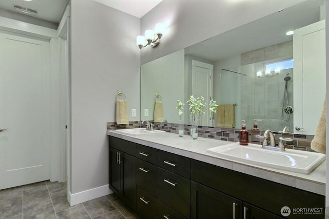 full bath featuring tasteful backsplash, visible vents, a walk in shower, and a sink