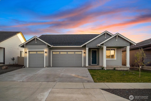 view of front of property with an attached garage, a yard, driveway, and a shingled roof