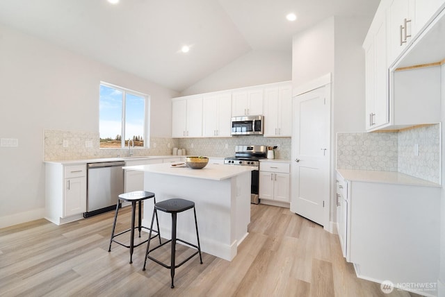 kitchen with a breakfast bar, appliances with stainless steel finishes, a center island, and light wood-style floors