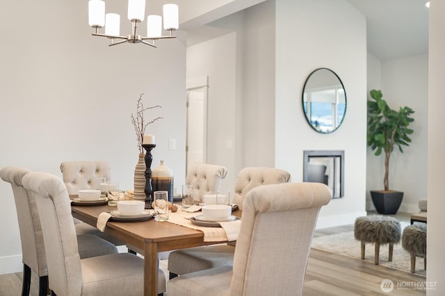 dining area featuring a high ceiling, an inviting chandelier, and wood finished floors