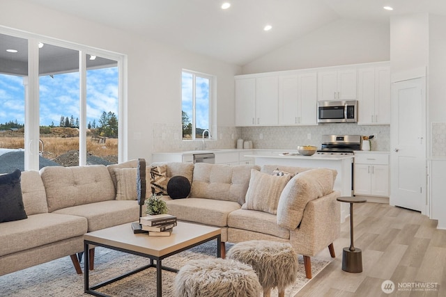 living room featuring recessed lighting, high vaulted ceiling, and light wood-type flooring