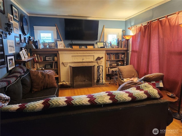 living area with crown molding, light wood-style flooring, and a brick fireplace