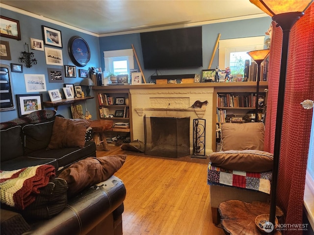 living room featuring a brick fireplace, wood finished floors, and ornamental molding