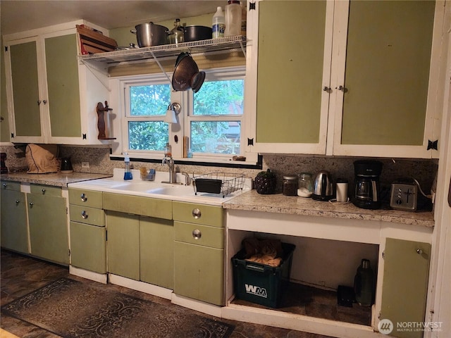 kitchen featuring tasteful backsplash, green cabinets, light countertops, and a sink