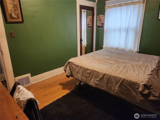 bedroom featuring wood finished floors, visible vents, and baseboards