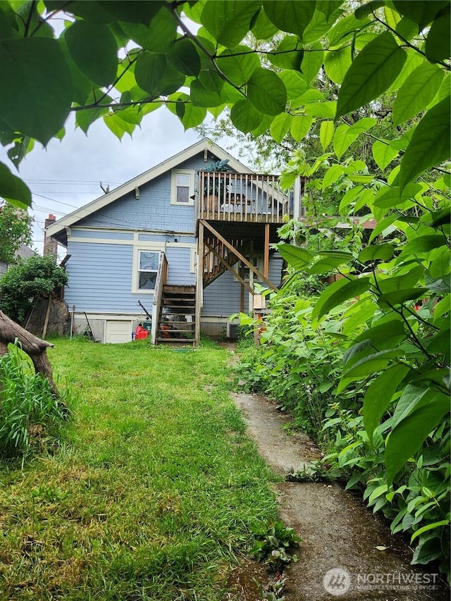 back of property featuring a deck, stairway, and a lawn