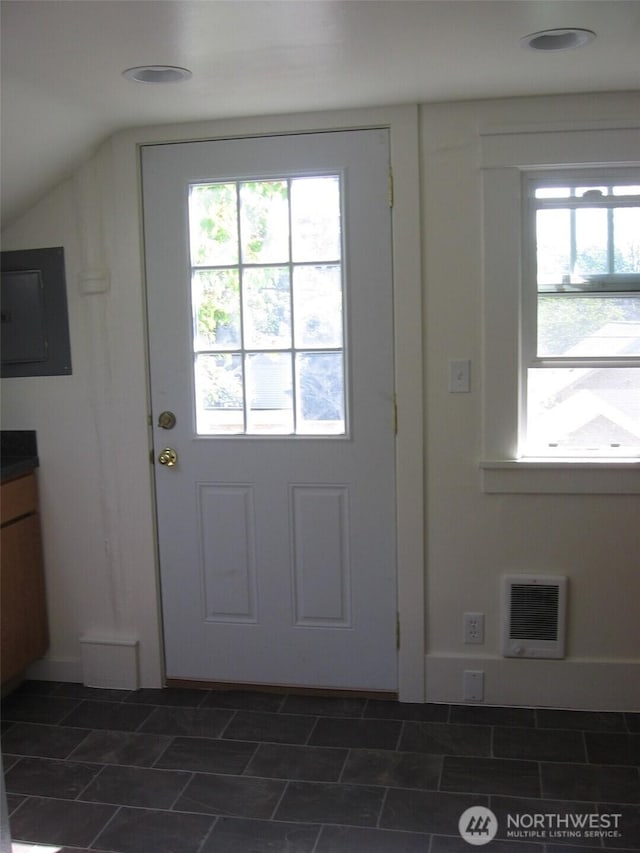 doorway to outside featuring electric panel, heating unit, and vaulted ceiling