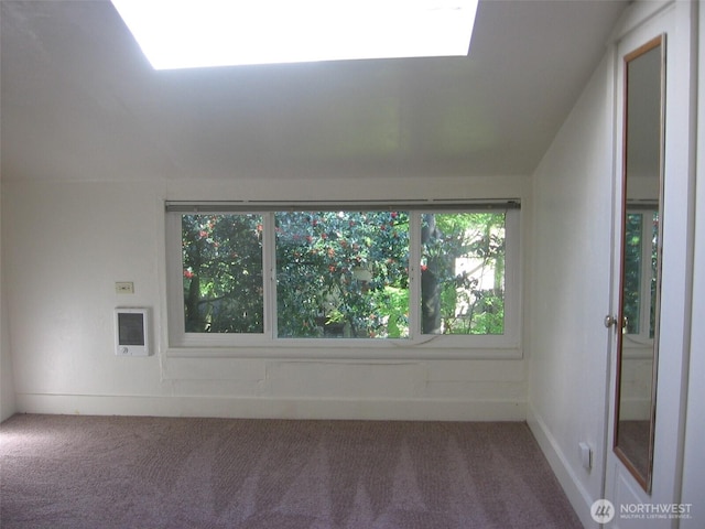 empty room with heating unit, lofted ceiling, and carpet flooring