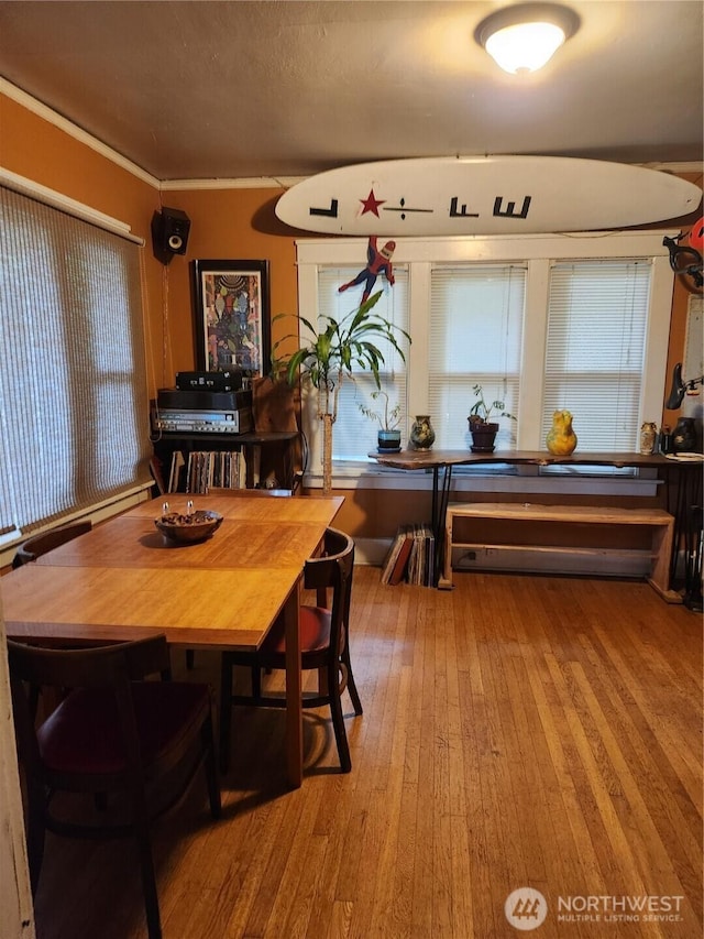 dining area featuring wood-type flooring and ornamental molding