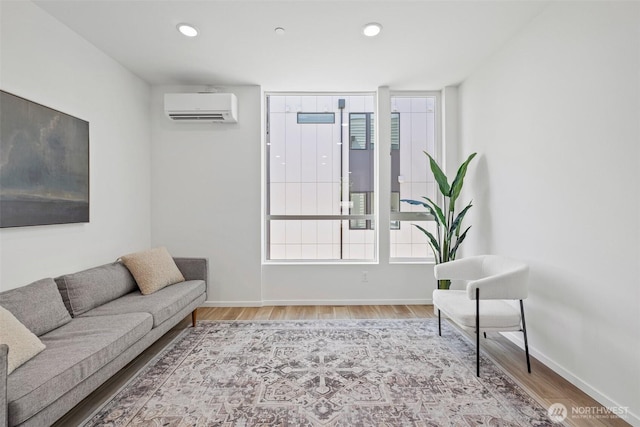 living area with recessed lighting, an AC wall unit, baseboards, and wood finished floors